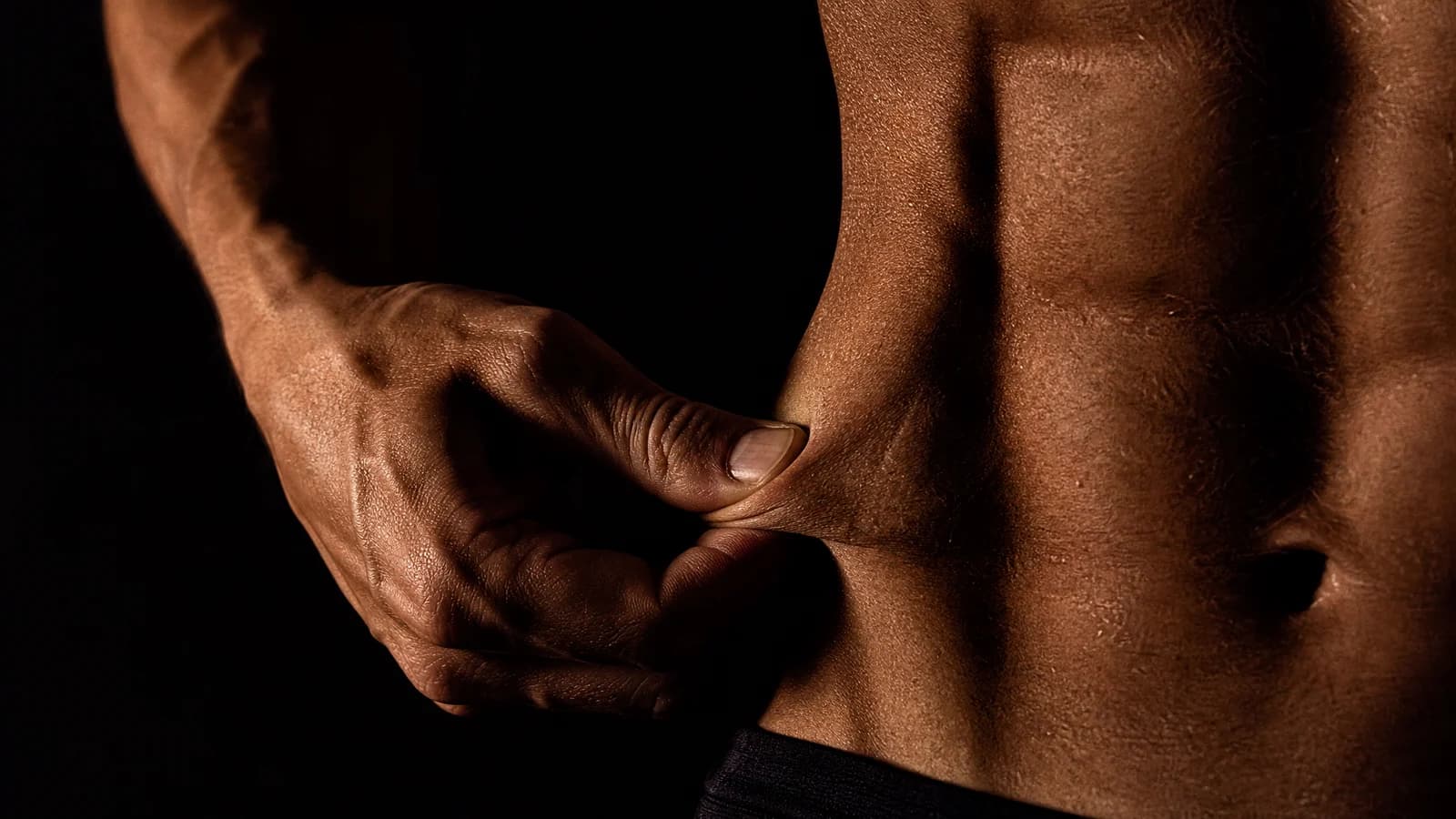 Hand pinching a thin skinfold on a lean torso